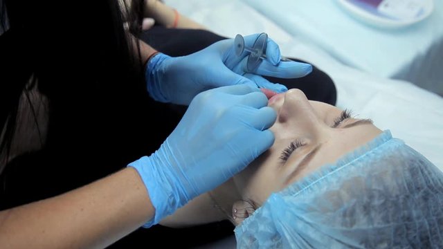 The cosmetic girl smoothes botox in the lips of the girl after the injection. Lip augmentation procedure