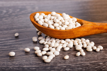 Pile of  white beans in a wooden spoon.