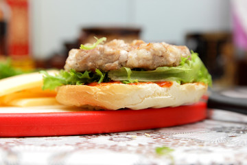 Cooking of burgers with veal, red tomatoes, lettuce, cheese and sauce in the home kitchen