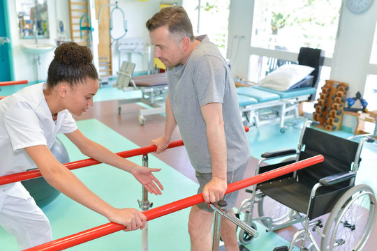 female therapist with man in parallel bars