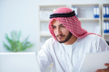 Arab businessman working in the office doing paperwork with a pi