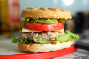 Cooking of burgers with veal, red tomatoes, lettuce, cheese and sauce in the home kitchen