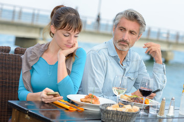 Couple having meal, woman using smartphone