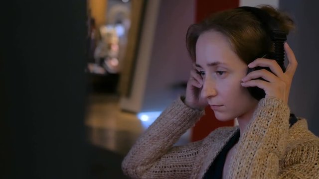 Woman touching interactive display, using headphones and listening audio guide at modern jewish history museum. Education and technology concept