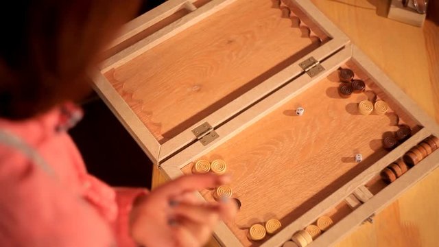 Two artistic girls play backgammon in a restaurant