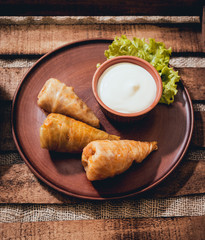 Tasty meat rolls with sour cream and salad on wooden table