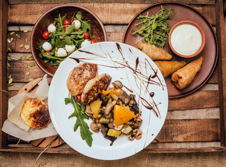 Tasty meat rolls with sour cream and salad on wooden table