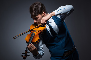 Young man playing violin in dark room