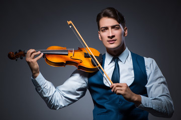 Young man playing violin in dark room