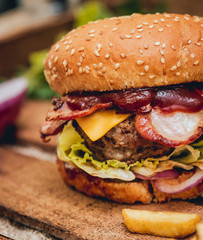 Bacon burger with beef and french fries on wooden table