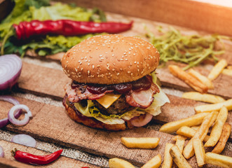 Bacon burger with beef and french fries on wooden table
