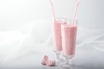 Pink milk and fruit cocktail and marshmallows on white background. Two jars of strawberry...