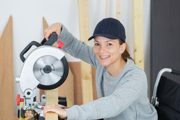 female carpenter in wheelchair is using a circular saw