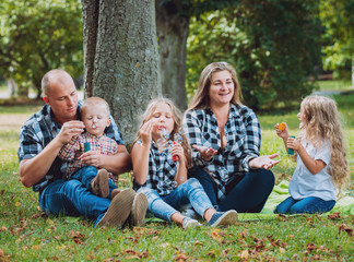 Fototapeta premium Young family with cheerful children in the park