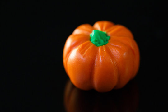litle polimer clay pumpkin on dark reflective background