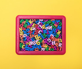 multicolored wooden letters of the English alphabet in a red frame