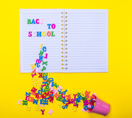 scattered wooden multicolored letters from an iron bucket on a notebook in a line