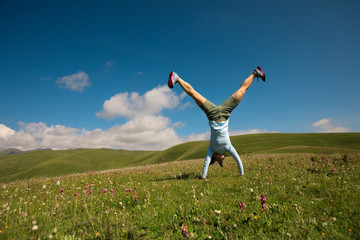 woman doing a handstand in a mountain peak meadow