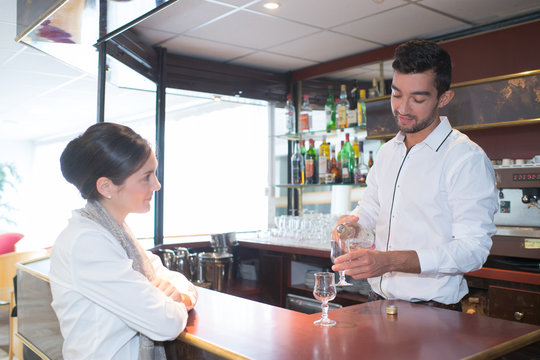 waiter serving a cocktail to woman at bar counter