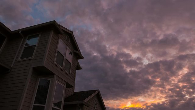 Colorful sunset and moving dramatic clouds over roof of residential suburb home in Happy Valley Oregon 4k ultra high definition time lapse video