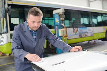 Man in bus garage cleaning panel