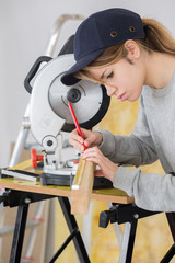 Female contractor marking position to saw wood