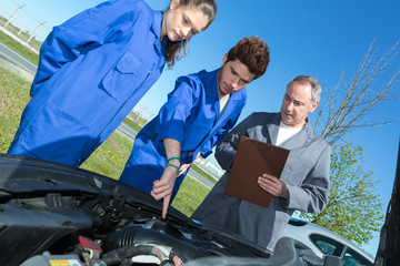 teacher helping students training to be car mechanics