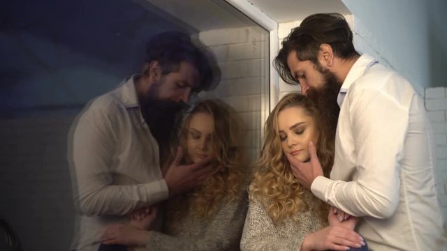 Couple date, love of man and woman. Young family in their own house or apartment. Tenderness and harmony in relationship. Bearded man loves blonde woman. New windows for house. Family near window