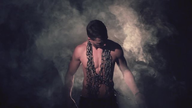 Man in metal chains in smoke