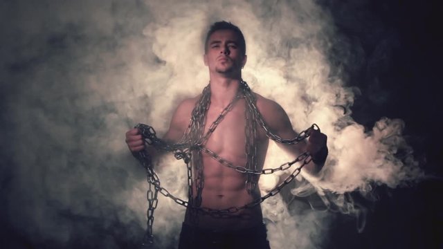 Man in metal chains in smoke
