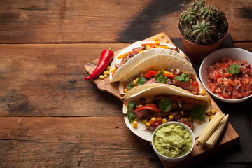 Three Mexican tacos with marbled beef, black Angus and vegetables on old rustic table. Mexican dish...