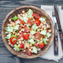 Chickpea salad with cherry tomatoes, cucumbers, basil and onion with citrus dressing, top view, square format