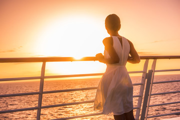 Obraz premium Cruise ship vacation woman travel watching sunset at sea ocean view. Elegant lady in white dress relaxing on deck balcony, luxury holiday destination.