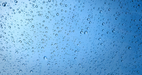 Rain drops on blue glass window background