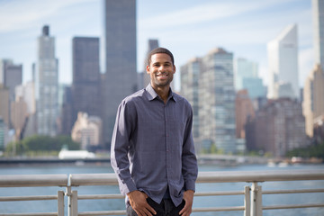 Portrait of young handsome African American man smiling, with NYC skyline in the background