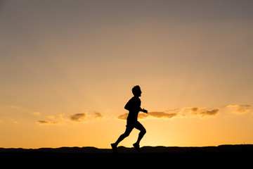 Fototapeta na wymiar Silhouette of a man running at sunset
