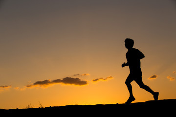 Silhouette of a man running at sunset