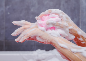 close up of woman washing hand with sponge in bathtub in the bathroom