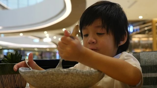 Cute Asian child eating japanese noodles in a restaurant slow motion 