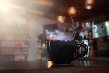 abstract blur hot black coffee in coffee shop with wooden table background.