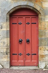 Red painted door set in an ancient stone wall