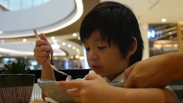 Cute Asian child eating japanese noodles in a restaurant slow motion 