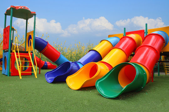 colorful playground park is build happy equipment children on blue sky, flower and grass background