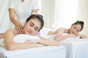 Fototapeta na wymiar Two cute young women enjoy relaxing during massage at spa.