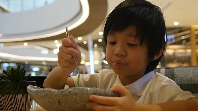Cute Asian child eating japanese noodles in a restaurant slow motion 