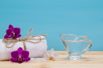 Obraz na płótnie Canvas Massage oil and towel for spa treatments, on a blue background