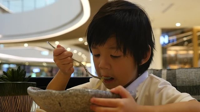 Cute Asian child eating japanese noodles in a restaurant slow motion 