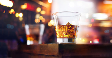 Whiskey glasses drinks with ice cubes on wooden table bar background