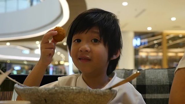 Cute Asian child eating japanese noodles in a restaurant slow motion 