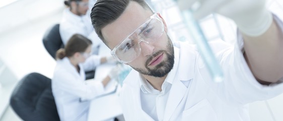 image is blurred. young scientist holding tube with the reagents